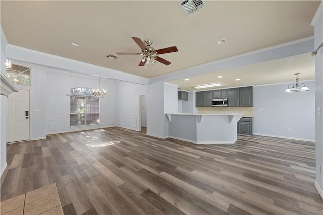 unfurnished living room with ceiling fan with notable chandelier, dark hardwood / wood-style flooring, and crown molding