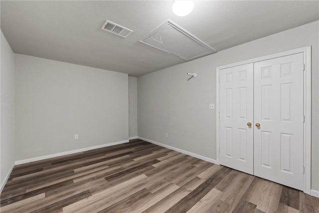 unfurnished bedroom with a textured ceiling, dark wood-type flooring, and a closet