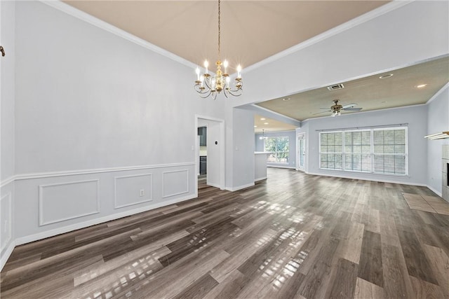 unfurnished dining area with ceiling fan with notable chandelier, dark hardwood / wood-style flooring, ornamental molding, and a tiled fireplace