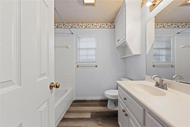 full bathroom with hardwood / wood-style floors, vanity, toilet, and tiled shower / bath