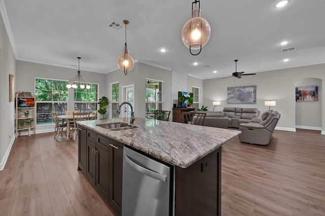 kitchen featuring stainless steel dishwasher, ceiling fan with notable chandelier, a kitchen island with sink, sink, and hanging light fixtures