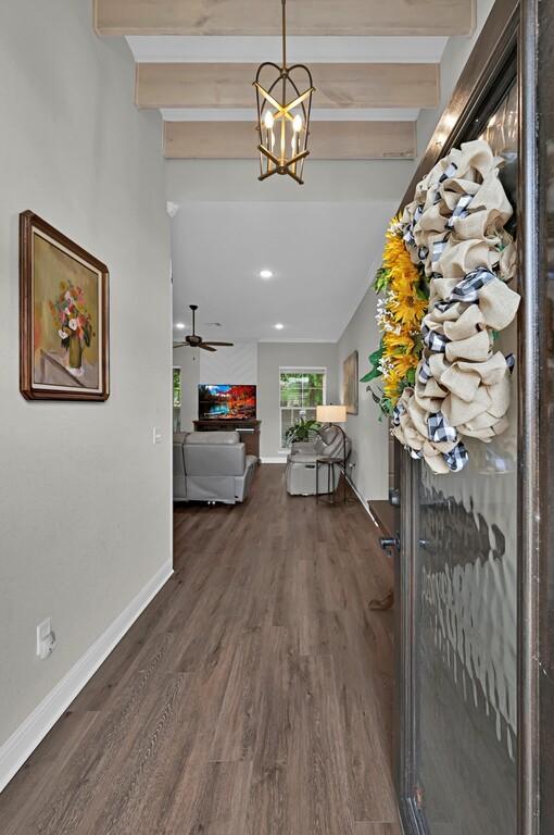 hallway with beamed ceiling, a notable chandelier, and dark hardwood / wood-style floors