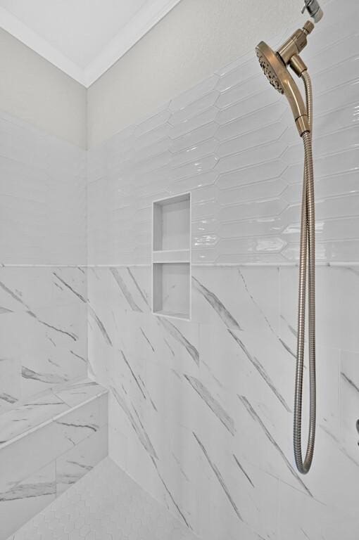 interior details with tiled shower and ornamental molding