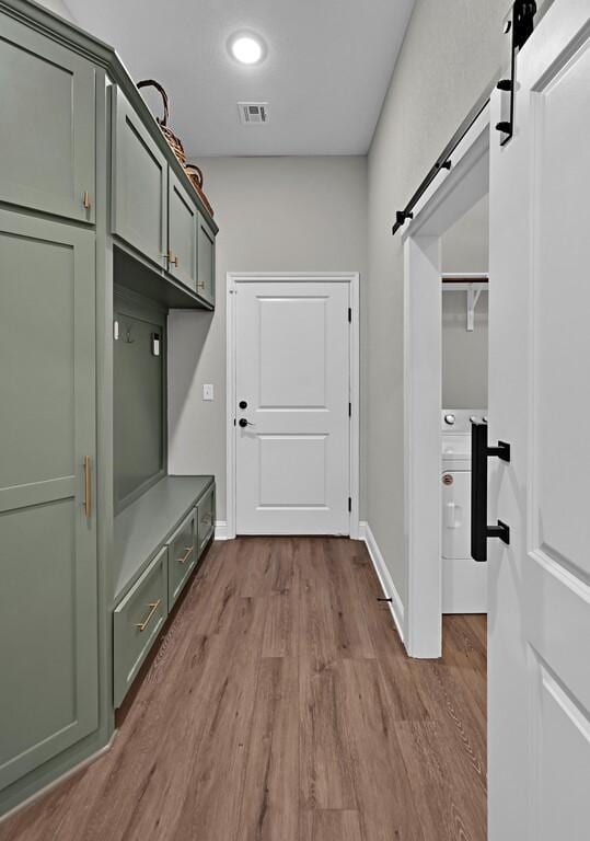 mudroom with a barn door and light hardwood / wood-style flooring