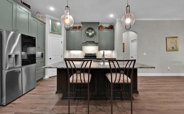 kitchen featuring light stone counters, sink, hanging light fixtures, and stainless steel refrigerator with ice dispenser