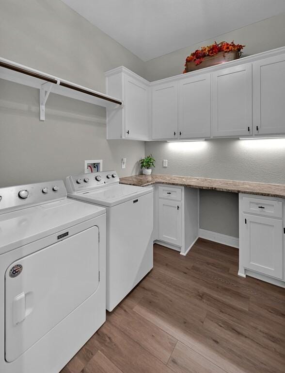 clothes washing area featuring cabinets, light hardwood / wood-style flooring, and washer and clothes dryer