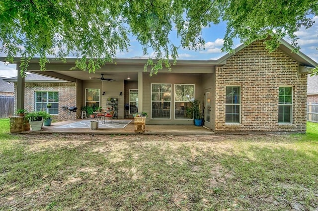 rear view of property featuring ceiling fan, a patio area, and a lawn