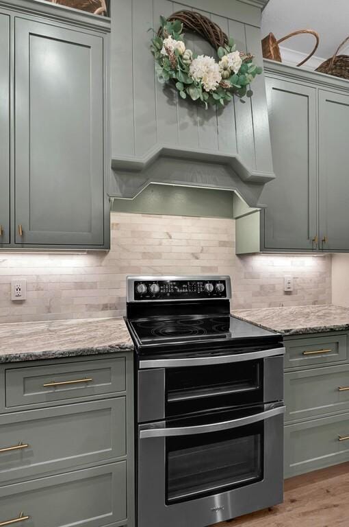 kitchen with decorative backsplash, light stone counters, stainless steel electric range oven, and light wood-type flooring