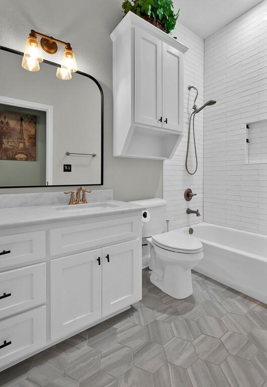 full bathroom featuring toilet, vanity, and tiled shower / bath