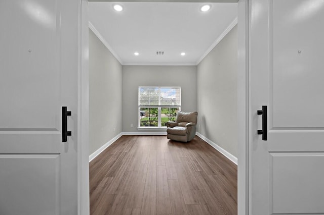 unfurnished room featuring hardwood / wood-style floors, a barn door, and ornamental molding