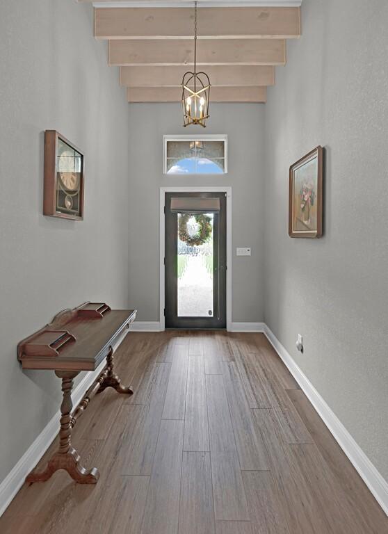 entryway with beamed ceiling, hardwood / wood-style flooring, and an inviting chandelier