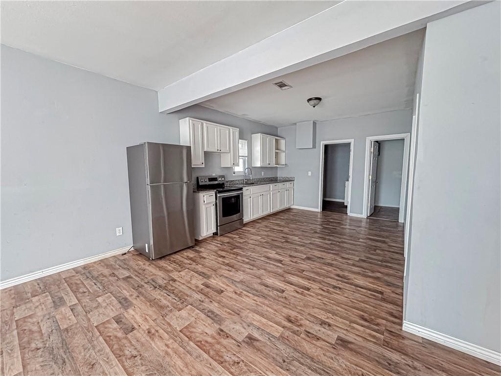 kitchen featuring stainless steel appliances, visible vents, white cabinets, wood finished floors, and baseboards