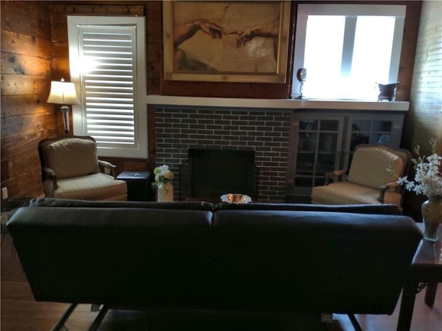 living room featuring wood walls and a tiled fireplace