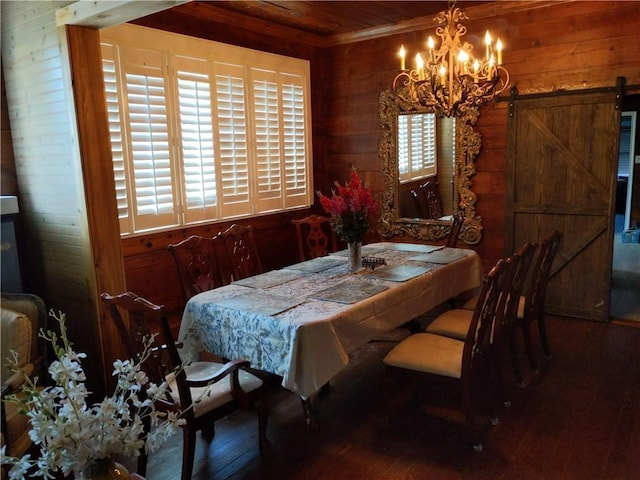 dining space featuring hardwood / wood-style flooring, a barn door, wooden walls, and a chandelier