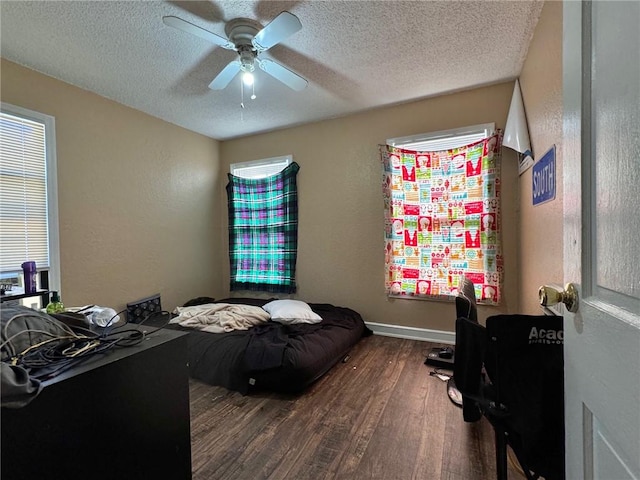 bedroom featuring a textured ceiling, multiple windows, ceiling fan, and dark hardwood / wood-style floors