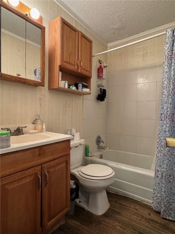 full bathroom featuring hardwood / wood-style floors, toilet, tile walls, a textured ceiling, and shower / tub combo with curtain