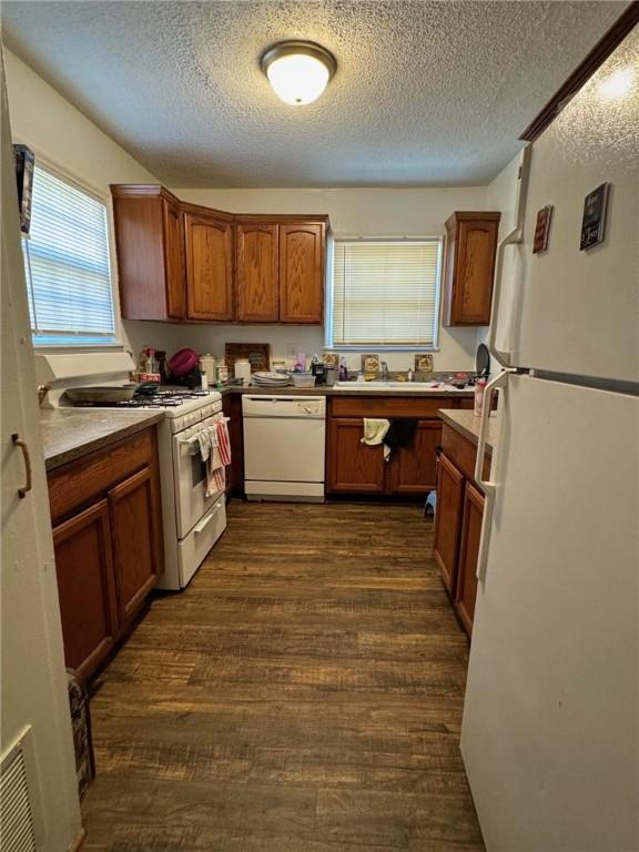 kitchen featuring a textured ceiling, white appliances, dark hardwood / wood-style floors, and sink