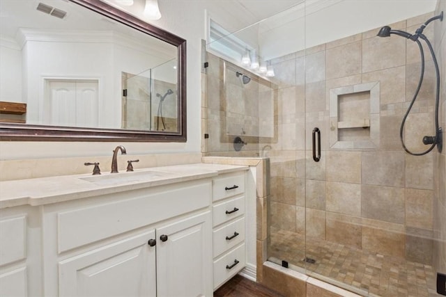 bathroom featuring wood-type flooring, vanity, a shower with shower door, and ornamental molding