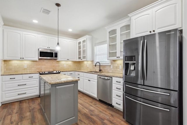 kitchen with sink, a kitchen island, pendant lighting, white cabinets, and appliances with stainless steel finishes