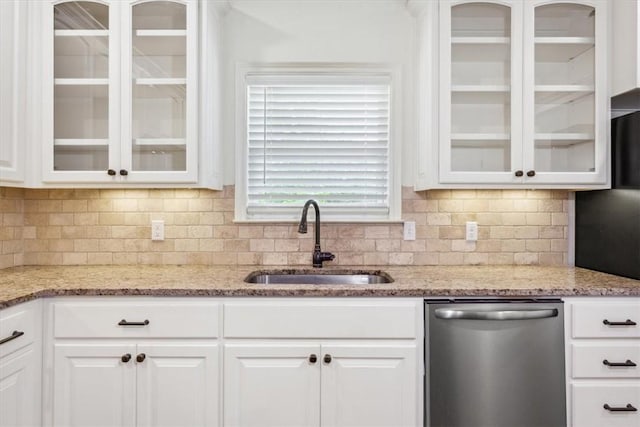 kitchen featuring backsplash, light stone counters, stainless steel dishwasher, sink, and white cabinetry