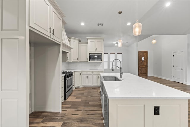 kitchen featuring pendant lighting, sink, stainless steel appliances, and a kitchen island with sink