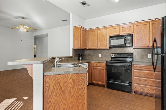 kitchen featuring black appliances, backsplash, kitchen peninsula, and sink