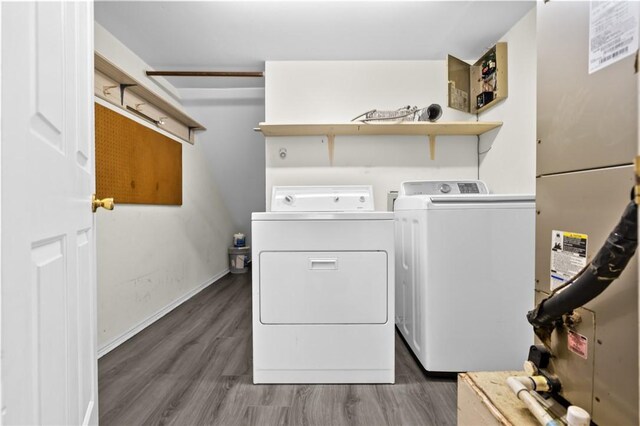 clothes washing area with washer and clothes dryer, heating unit, and dark hardwood / wood-style flooring