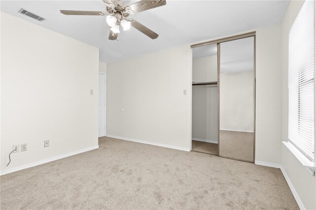 unfurnished bedroom featuring light carpet, a closet, and ceiling fan