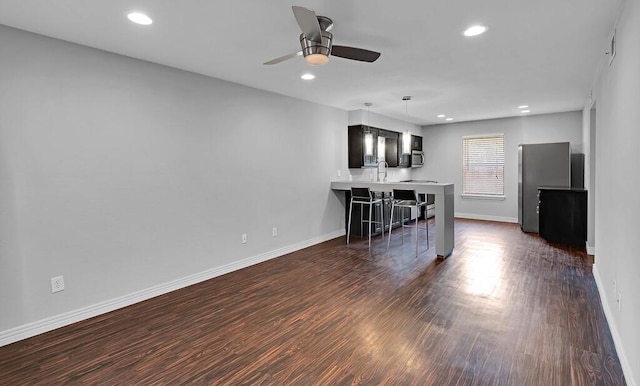 unfurnished living room with baseboards, recessed lighting, dark wood-style floors, a ceiling fan, and a sink