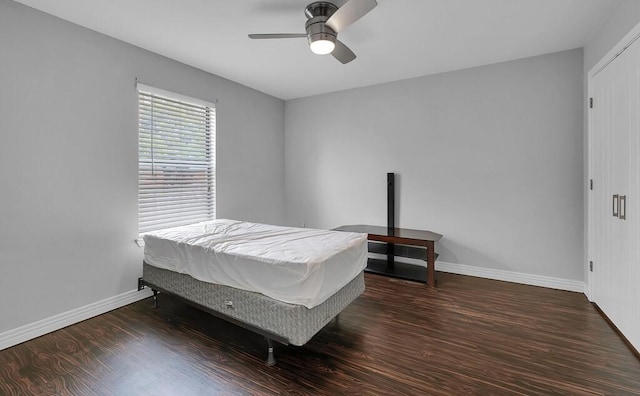 bedroom featuring baseboards, wood finished floors, and a ceiling fan