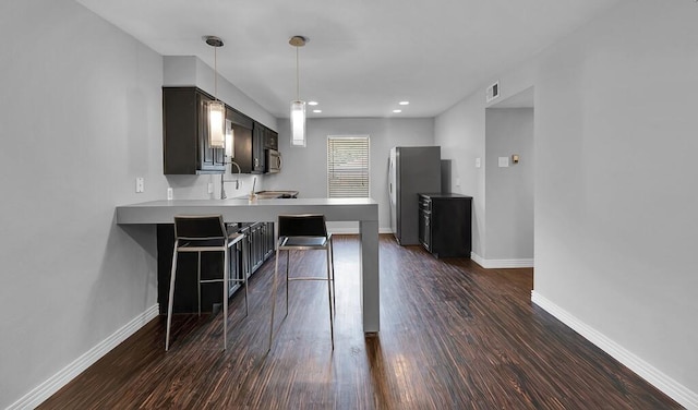 kitchen featuring a peninsula, stainless steel appliances, dark wood-type flooring, and a kitchen breakfast bar