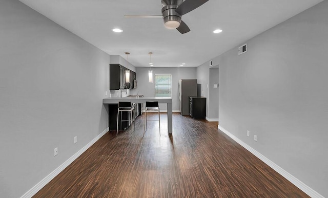 unfurnished living room featuring visible vents, baseboards, dark wood finished floors, and a ceiling fan