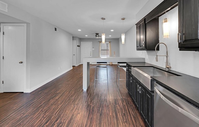 kitchen featuring dark wood finished floors, recessed lighting, stainless steel dishwasher, hanging light fixtures, and a sink