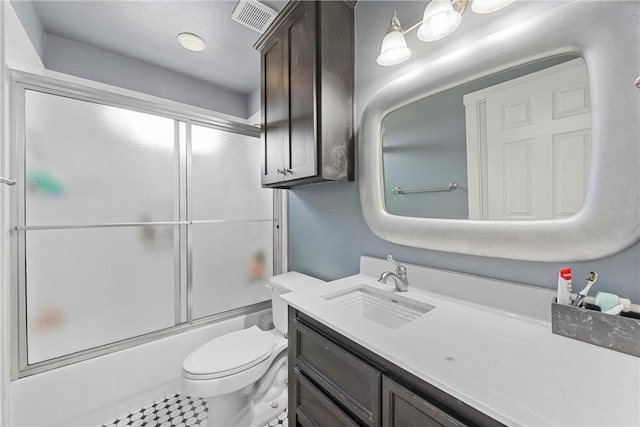 full bathroom with tile patterned floors, vanity, bath / shower combo with glass door, and toilet