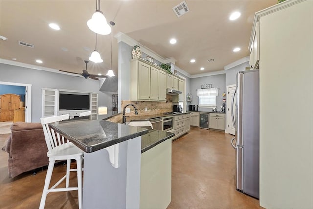 kitchen featuring sink, hanging light fixtures, stainless steel appliances, kitchen peninsula, and a breakfast bar