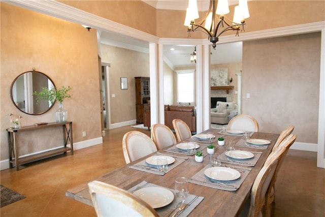 dining area with ornamental molding, a fireplace, baseboards, and ceiling fan with notable chandelier