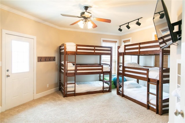 unfurnished bedroom featuring carpet floors, baseboards, crown molding, and track lighting