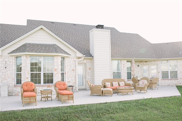 rear view of property featuring stone siding, roof with shingles, french doors, a patio area, and an outdoor living space