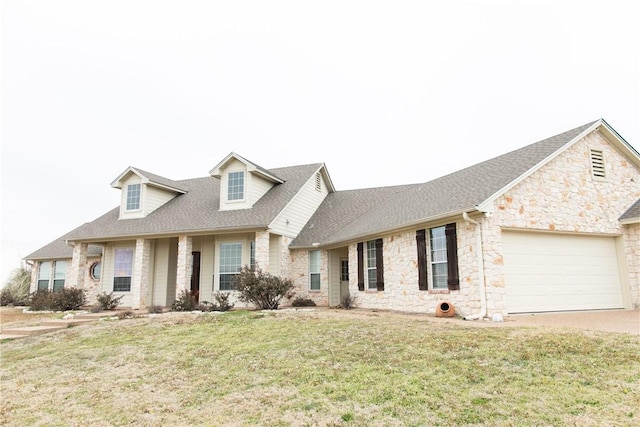 new england style home with a garage, a front yard, stone siding, and a shingled roof