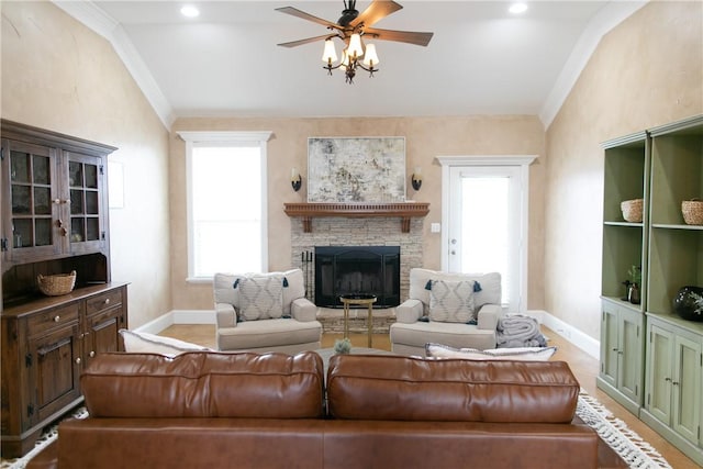 living room featuring ceiling fan, a fireplace, baseboards, and crown molding