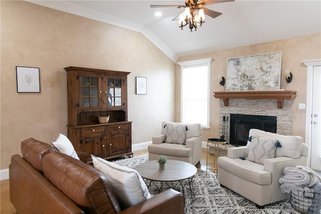 living area with a fireplace, lofted ceiling, ornamental molding, ceiling fan, and baseboards