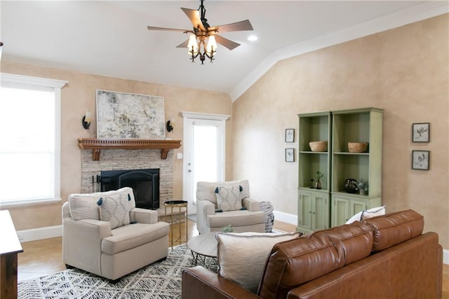 living area with a fireplace with raised hearth, a ceiling fan, baseboards, vaulted ceiling, and crown molding