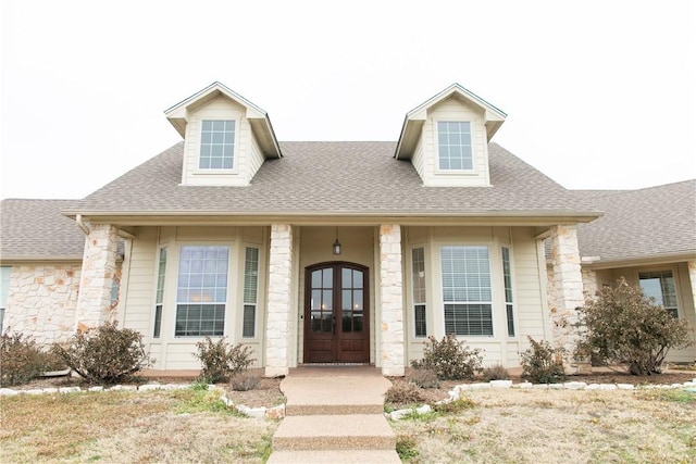 view of front facade featuring stone siding, french doors, and roof with shingles