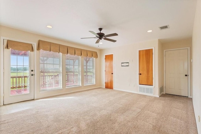 empty room with plenty of natural light, ceiling fan, and light carpet