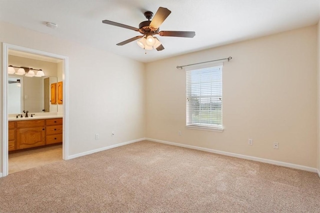 unfurnished bedroom featuring connected bathroom, light colored carpet, ceiling fan, and sink