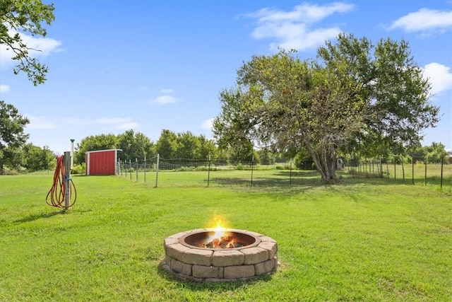 view of yard featuring a rural view, a shed, and an outdoor fire pit