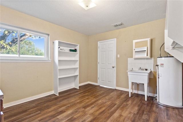 interior space with dark hardwood / wood-style floors, sink, a textured ceiling, and water heater