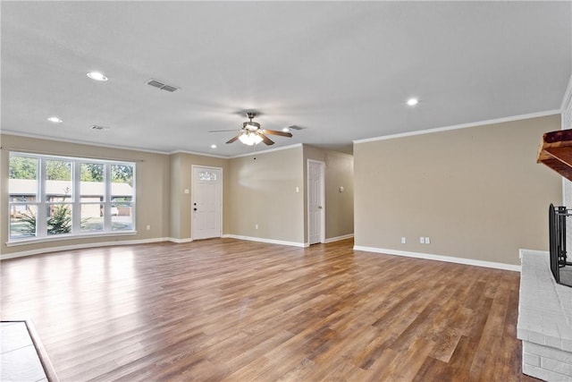 unfurnished living room featuring ceiling fan, light hardwood / wood-style floors, ornamental molding, and a brick fireplace