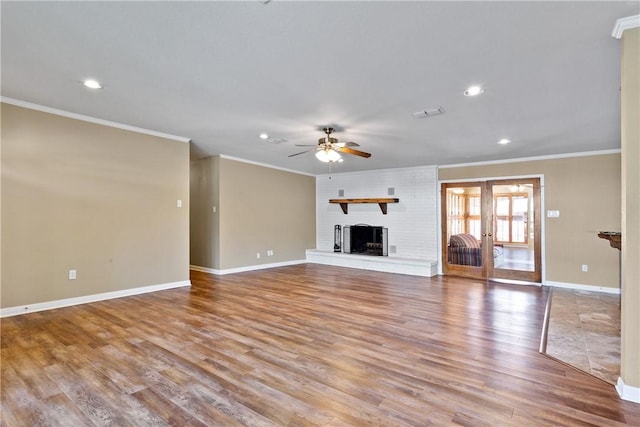 unfurnished living room featuring ceiling fan, french doors, a brick fireplace, light hardwood / wood-style flooring, and ornamental molding