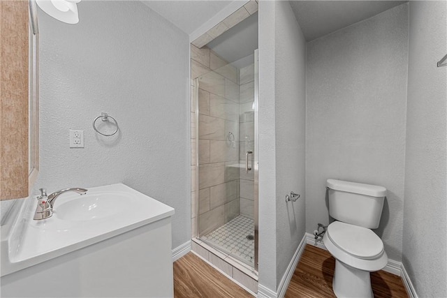 bathroom featuring toilet, a shower with door, vanity, and hardwood / wood-style flooring